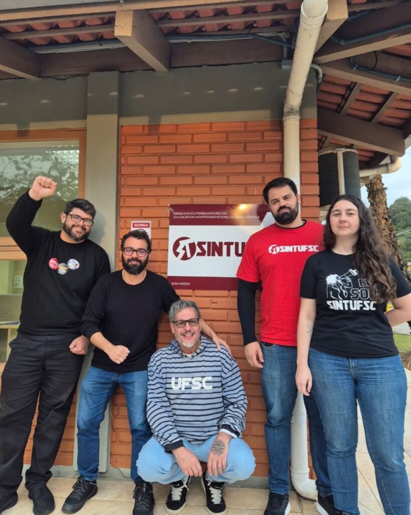 Fotografia tirada em frente à sede do Sintufsc. Nela estão 4 membros da direção do SINTUFSC junto ao candidato à deputado federal, Professor Canguru (PSOL)