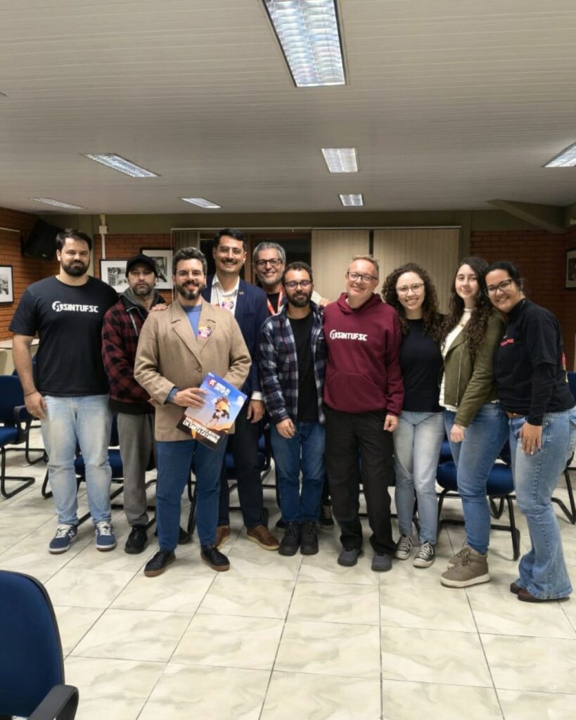 Fotografia tirada no auditório do SINTUFSC. Nela estão diversos membros da direção do Sindicato junto ao candidato à deputado estudual, Camasão (PSOL)