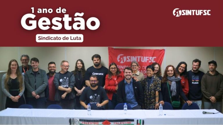 Ao fundo imagem da gestão "Sindicado de luta" no momento de poss. Na parte superior da imagem uma faixa vermelha com o título: "1 ano de gestão", abaixo em letras menores: "Sindicato de Luta"